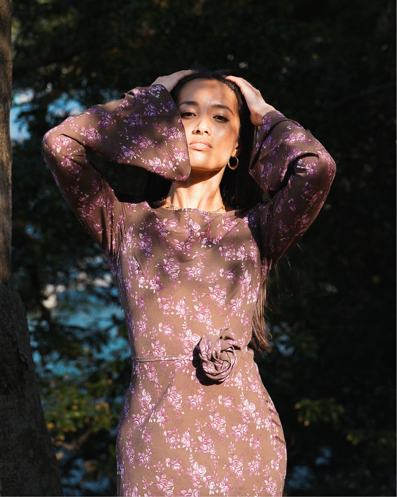 Woman wearing a floral dress standing outdoors with trees in the background
